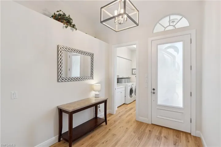 Entryway with a notable chandelier, light wood-type flooring, and independent washer and dryer