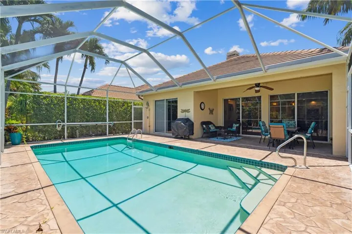 View of swimming pool featuring ceiling fan, glass enclosure, a patio area, and area for grilling