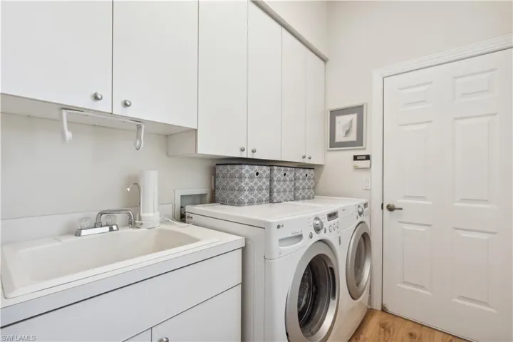 Washroom featuring hookup for a washing machine, light wood-type flooring, washing machine and dryer, sink, and cabinets