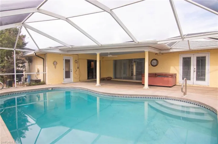 Outdoor pool featuring a sunroom, a patio area, french doors, and glass enclosure