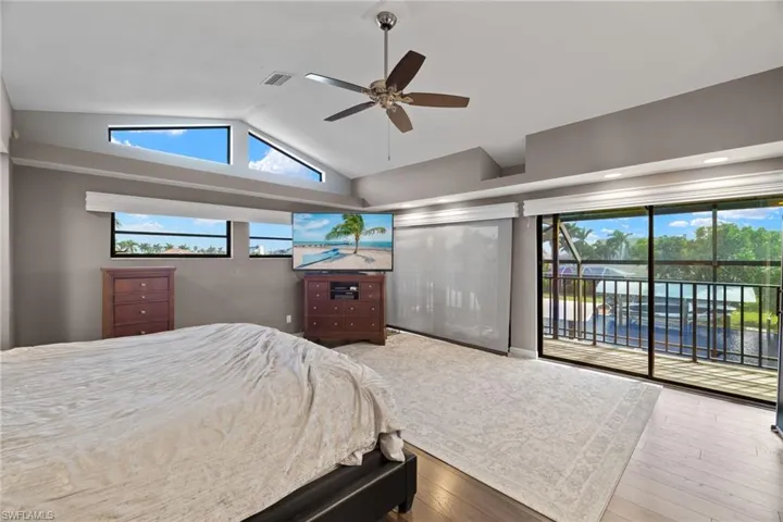Bedroom featuring ceiling fan, hardwood / wood-style flooring, lofted ceiling, and multiple windows