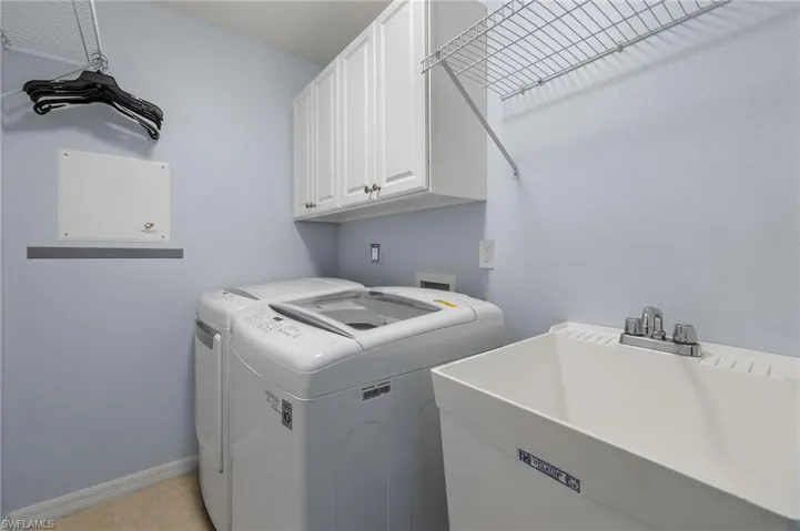Washroom with hookup for a washing machine, sink, cabinets, and washing machine and dryer