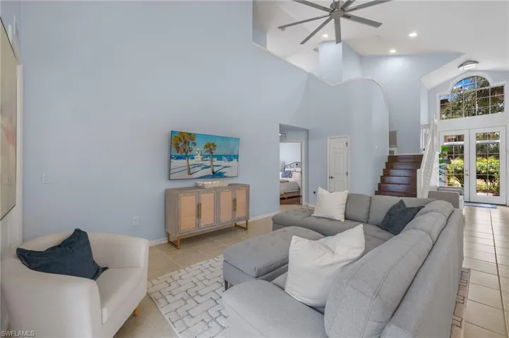 Living room featuring a high ceiling, french doors, ceiling fan, and light tile floors