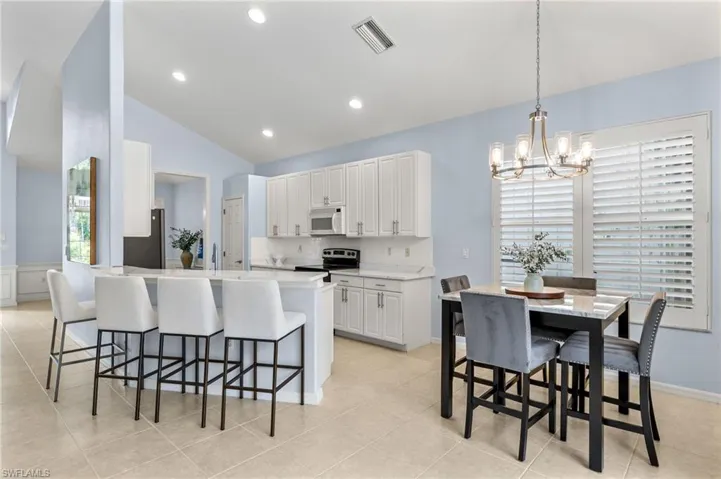 Kitchen with white cabinetry, a kitchen breakfast bar, electric range, and light tile floors