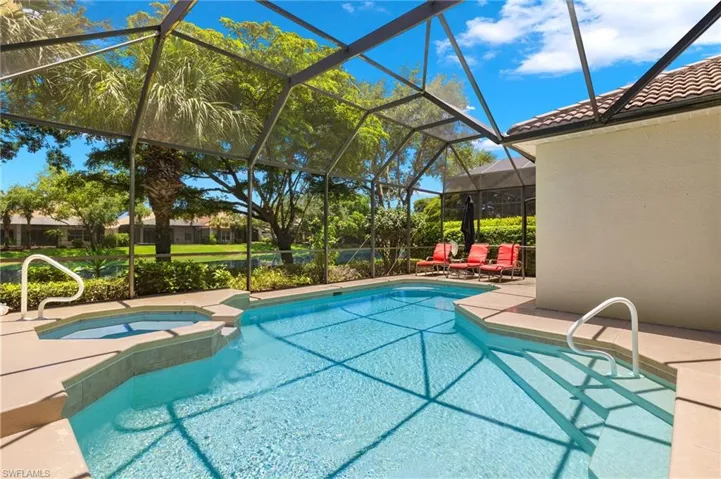View of pool featuring a patio area, glass enclosure, and an in ground hot tub