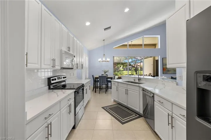 Kitchen featuring a chandelier, stainless steel appliances, hanging light fixtures, white cabinets, and light tile floors