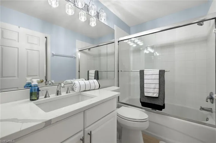 Full bathroom featuring shower / bath combination with glass door, oversized vanity, and toilet