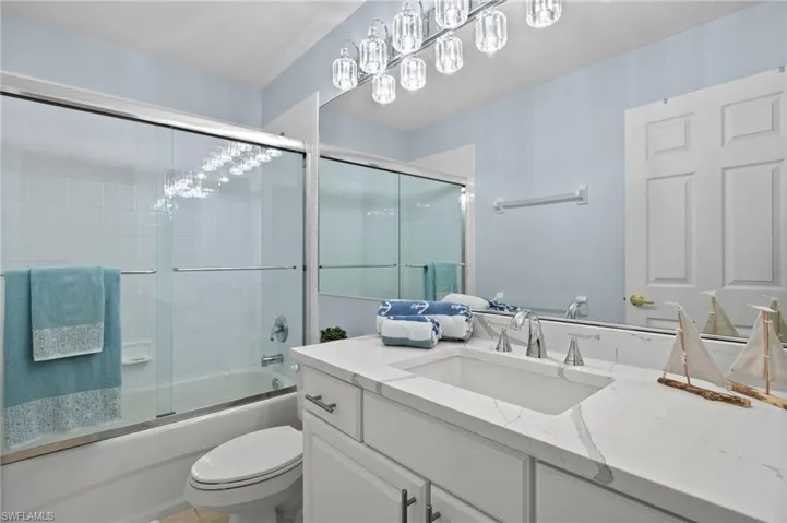 Full bathroom featuring enclosed tub / shower combo, vanity, and toilet