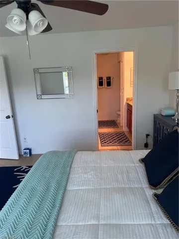 Tiled bedroom featuring ceiling fan and connected bathroom
