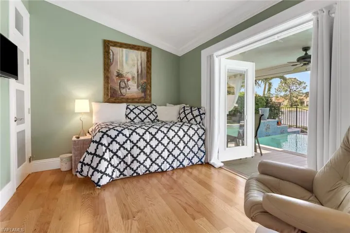 Bedroom featuring lofted ceiling, light wood-type flooring, crown molding, and access to outside