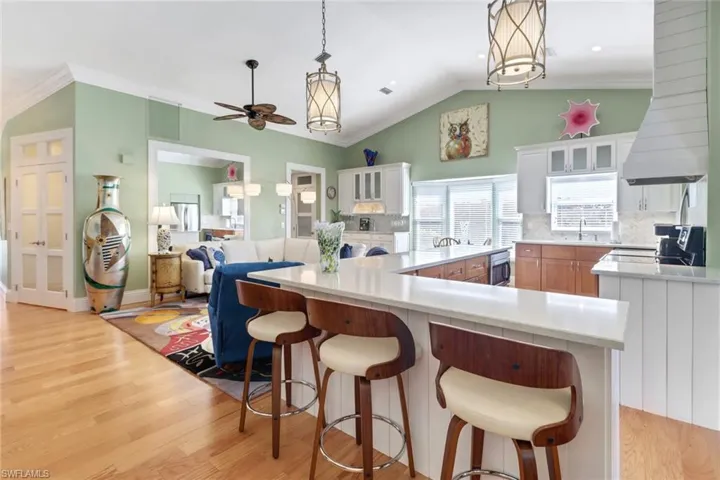 Kitchen featuring white cabinetry, ceiling fan, range hood, light hardwood / wood-style floors, and a kitchen island
