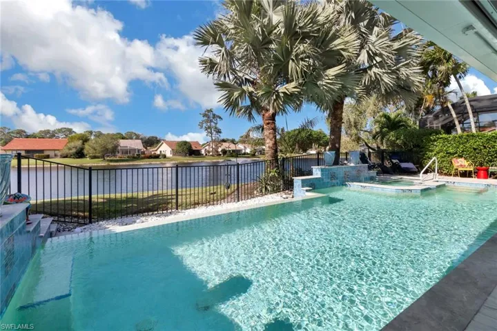 View of swimming pool with an in ground hot tub and a water view