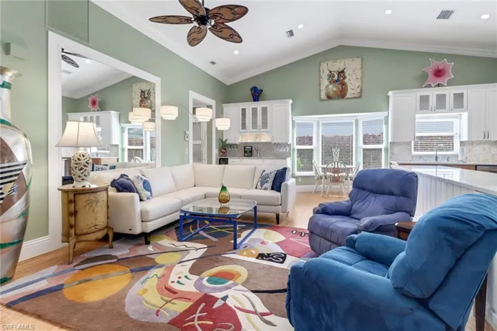 Living room featuring ceiling fan, ornamental molding, and light wood-type flooring