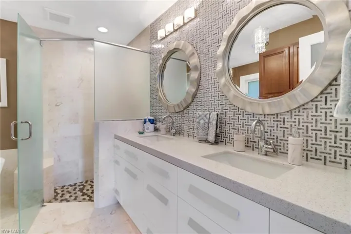 Bathroom with tasteful backsplash, a shower with door, vanity, and tile walls