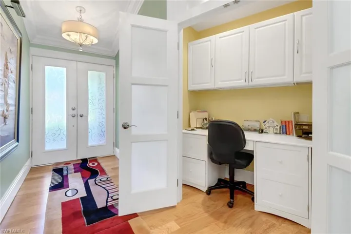 Office area featuring ornamental molding, french doors, built in desk, and light wood-type flooring