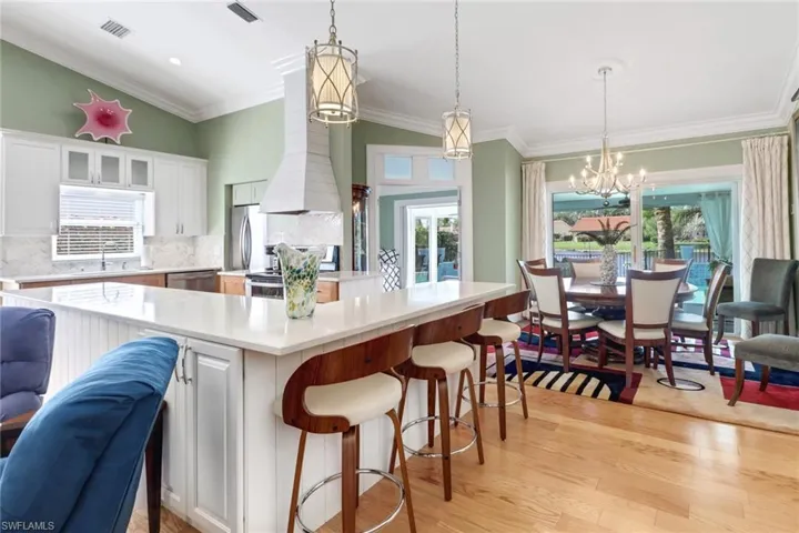Kitchen featuring white cabinets, light wood-type flooring, and hanging light fixtures