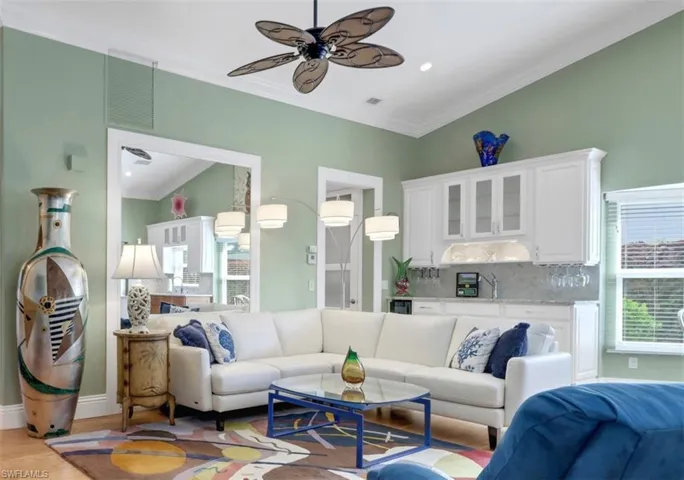 Living room with light hardwood / wood-style floors, ceiling fan, ornamental molding, and sink