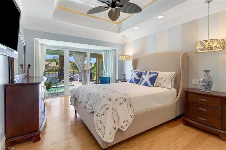 Bedroom featuring access to exterior, ornamental molding, a tray ceiling, ceiling fan, and light hardwood / wood-style floors