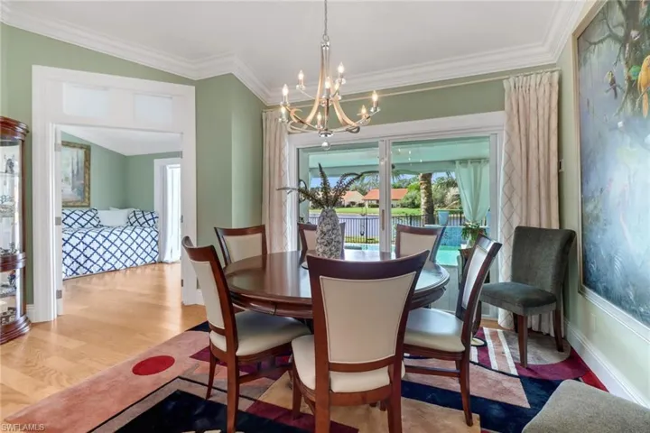 Dining area with a notable chandelier, light wood-type flooring, and crown molding
