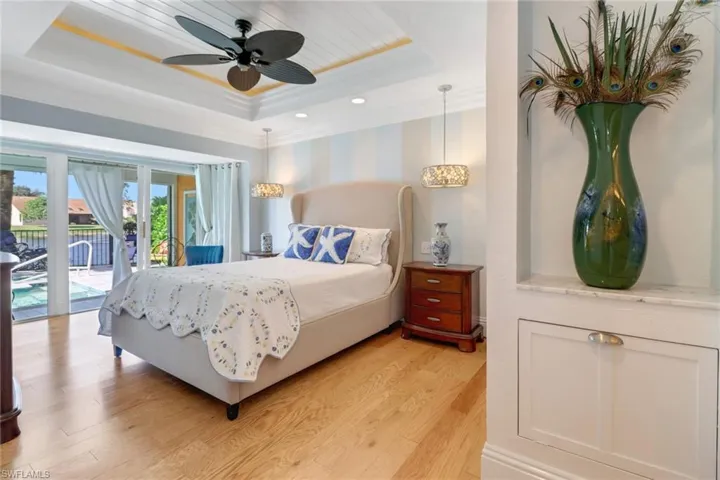 Bedroom with a raised ceiling, access to exterior, ceiling fan, and light hardwood / wood-style floors