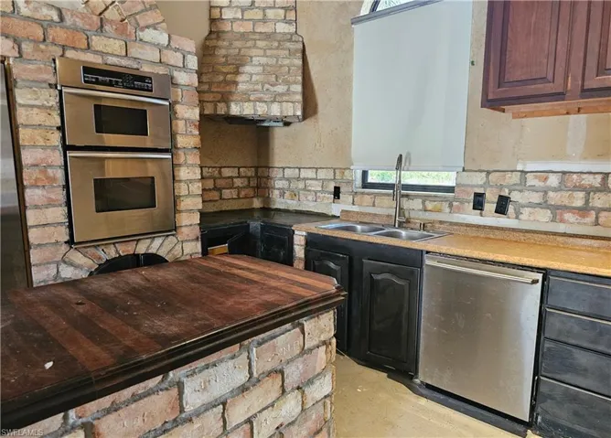 Kitchen featuring healthy amount of natural light, appliances with stainless steel finishes, and concrete floors