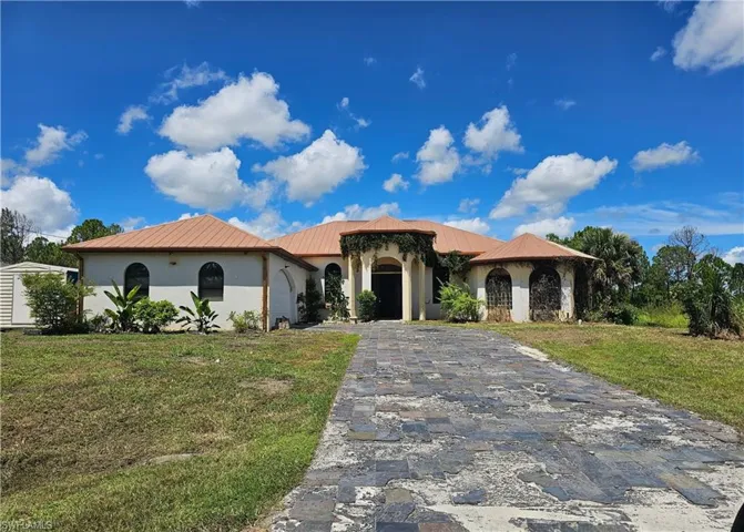 Mediterranean / spanish home with decorative driveway, stucco siding, a garage, a front yard, and a metal roof
