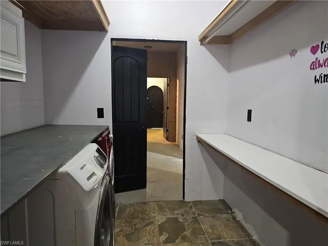 Laundry room featuring arched walkways and washer and clothes dryer