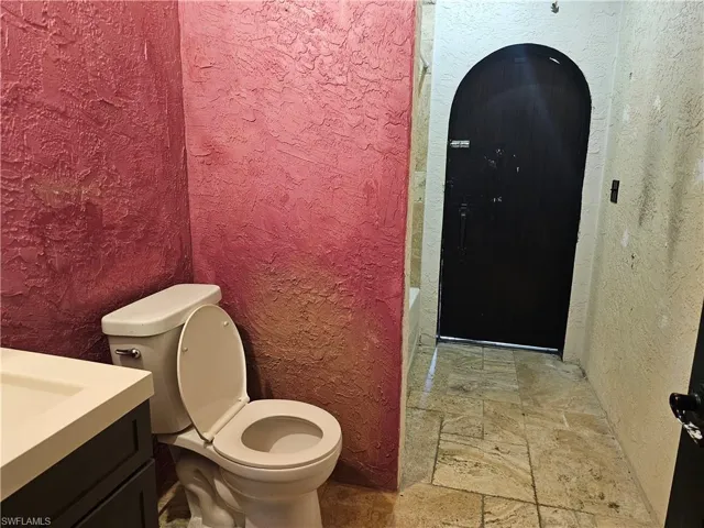 Bathroom with a textured wall, stone tile floors, and vanity