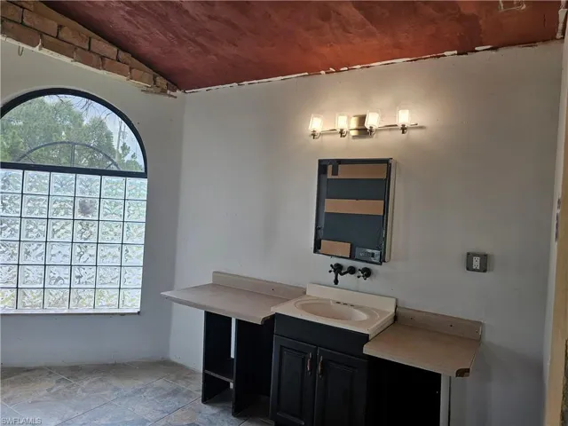 Bathroom with vanity, lofted ceiling, and light stone finish floors