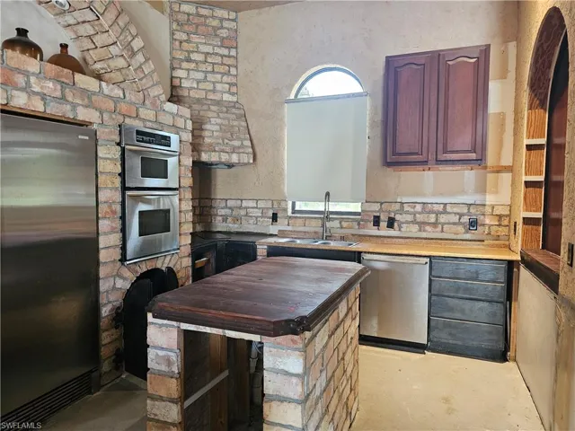 Kitchen with stainless steel appliances, concrete flooring, and butcher block countertops