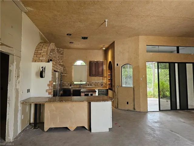 Kitchen featuring concrete flooring, a peninsula, high quality fridge, tasteful backsplash, and a textured ceiling
