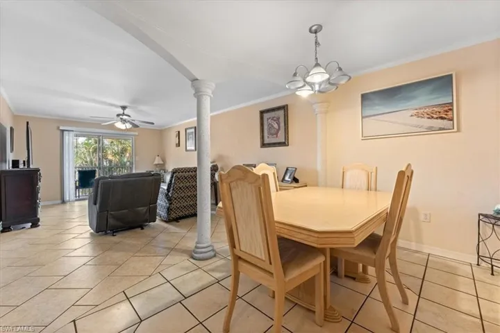 Dining area featuring decorative columns, crown molding, a ceiling fan, light tile patterned flooring, and baseboards