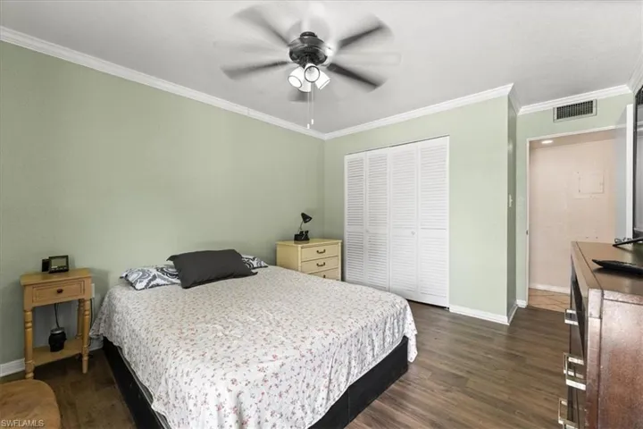 Bedroom with baseboards, dark wood-style floors, ornamental molding, a closet, and ceiling fan