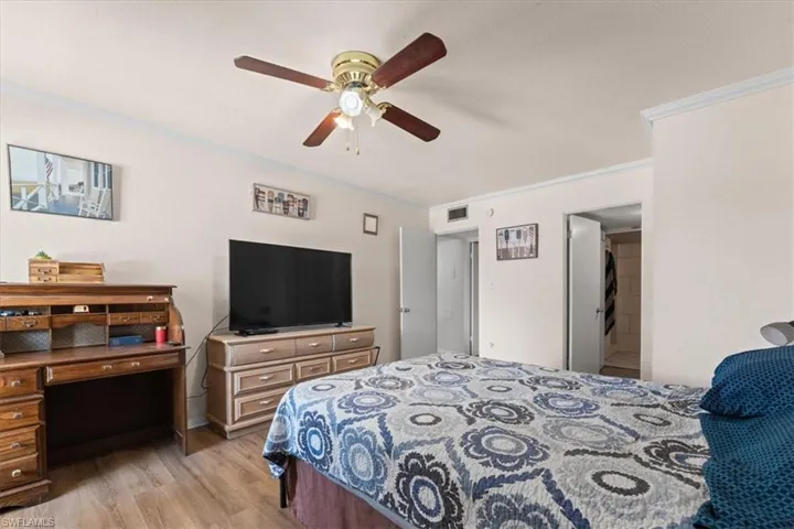 Bedroom with light wood-type flooring, ornamental molding, and ceiling fan