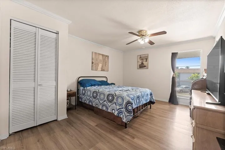 Bedroom with wood finished floors, ornamental molding, baseboards, a closet, and a ceiling fan
