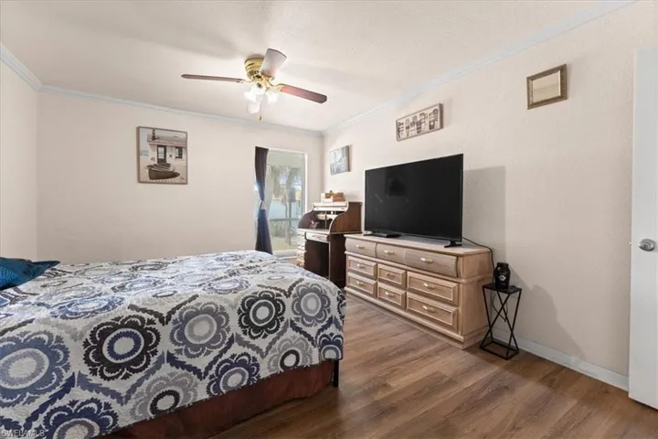 Bedroom with wood finished floors, crown molding, baseboards, access to outside, and ceiling fan