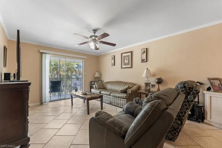 Living room with crown molding, a ceiling fan, and light tile patterned flooring