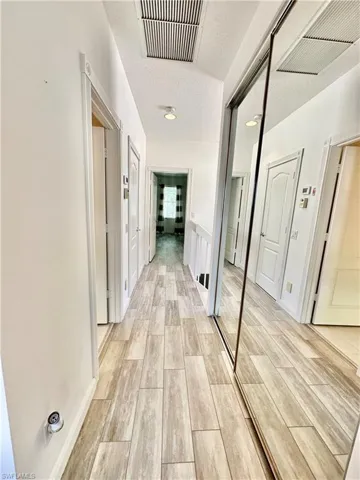 Hallway featuring wood-look tile flooring, white baseboards, and bright white walls