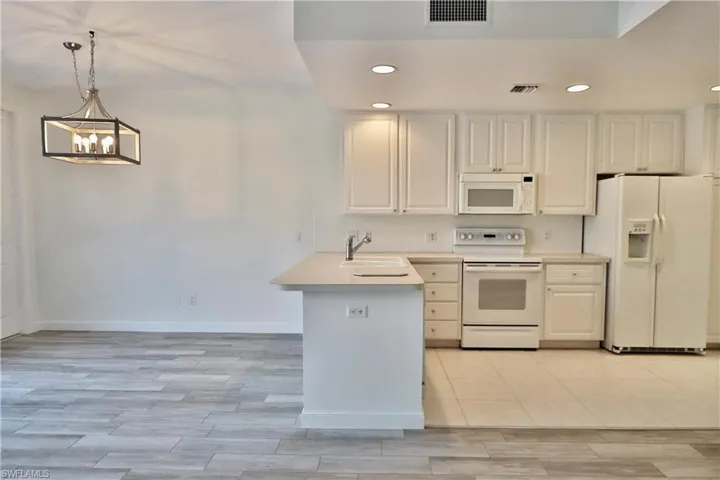 Modern kitchen featuring white cabinetry, light-toned countertops, and a full suite of white appliances