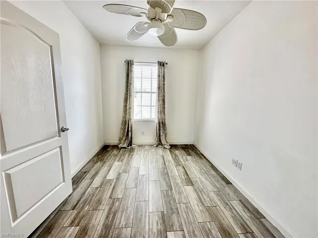 Room featuring wood-finish flooring, a window with blinds and drapes, and a ceiling fan