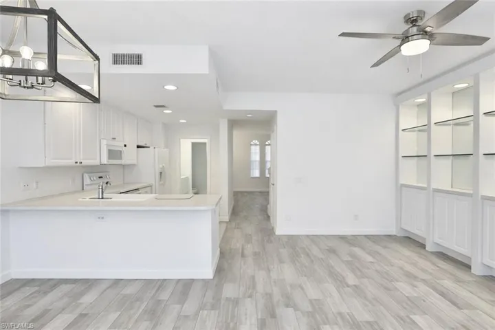 Bright kitchen with white cabinetry and light-toned countertop, featuring a breakfast bar