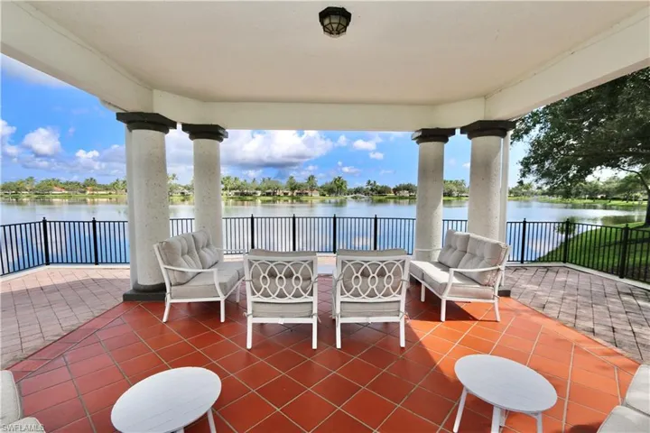 Covered patio with red-toned tile flooring, supported by substantial columns