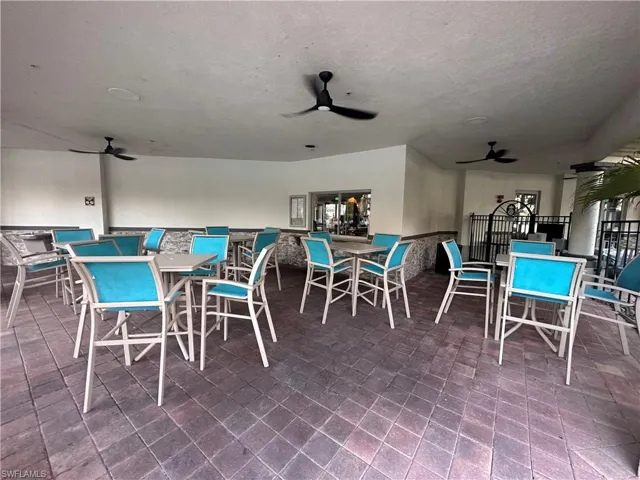 Covered outdoor patio featuring extensive paver flooring, multiple ceiling fans, recessed lighting, and a service window