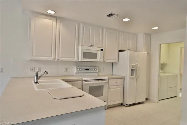 Kitchen featuring white cabinetry, light-toned countertops, white tile flooring, and recessed lighting
