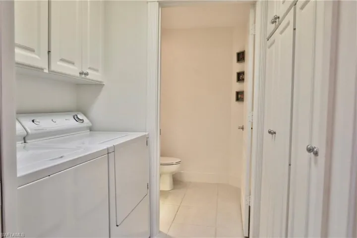 Dedicated laundry area with upper cabinetry and a separate commode room