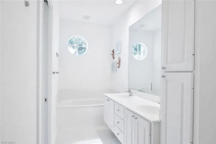 Bathroom featuring a double vanity with white cabinetry, dual undermount sinks, and a large wall-mounted mirror