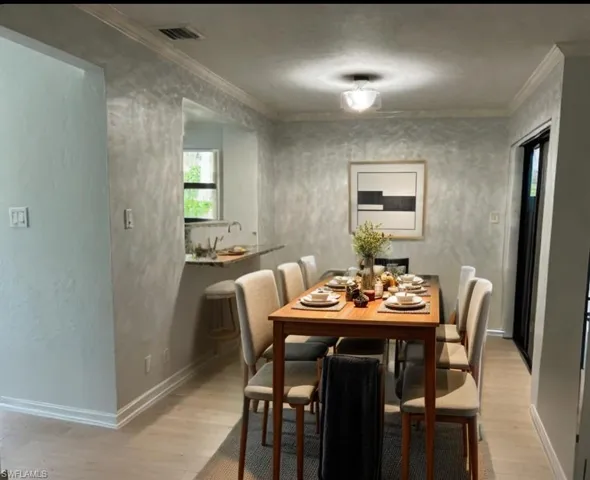 Dining space with ornamental molding and light hardwood / wood-style floors