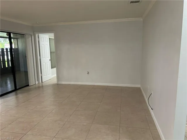 Tiled spare room featuring crown molding