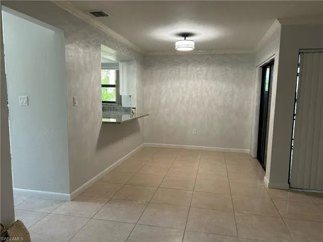 Hall with ornamental molding and light tile floors