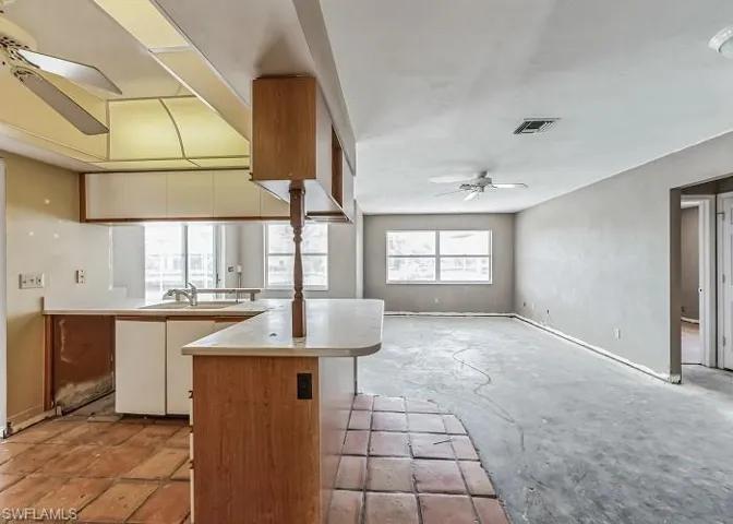Kitchen featuring sink, a kitchen island, ceiling fan, and light tile floors
